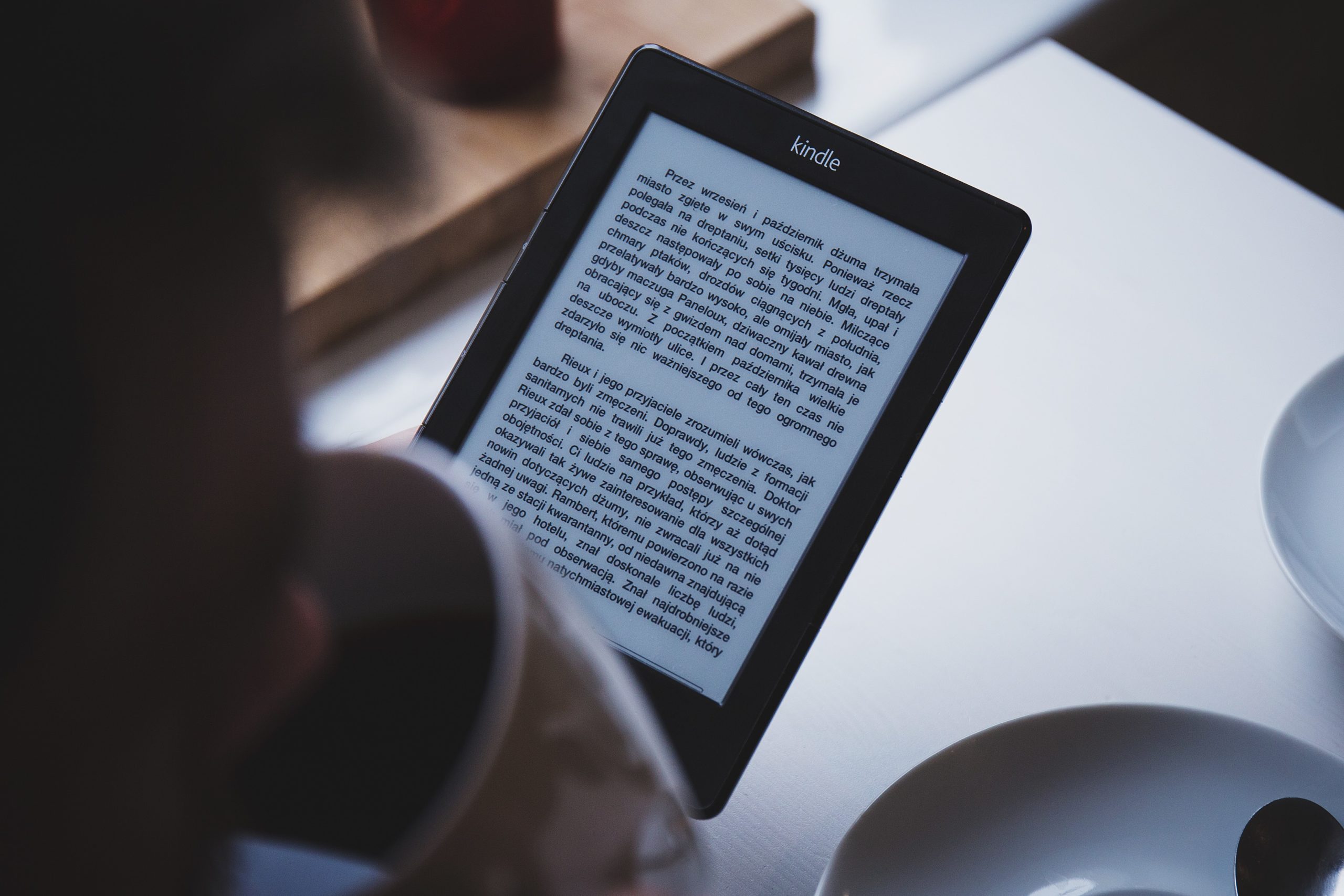 Woman reading an ebook on a Kindle with her morning coffee