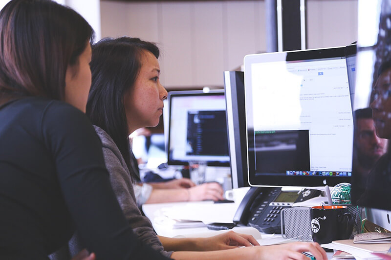 Two females reviewing data on a computer screen for marketing strategy creation
